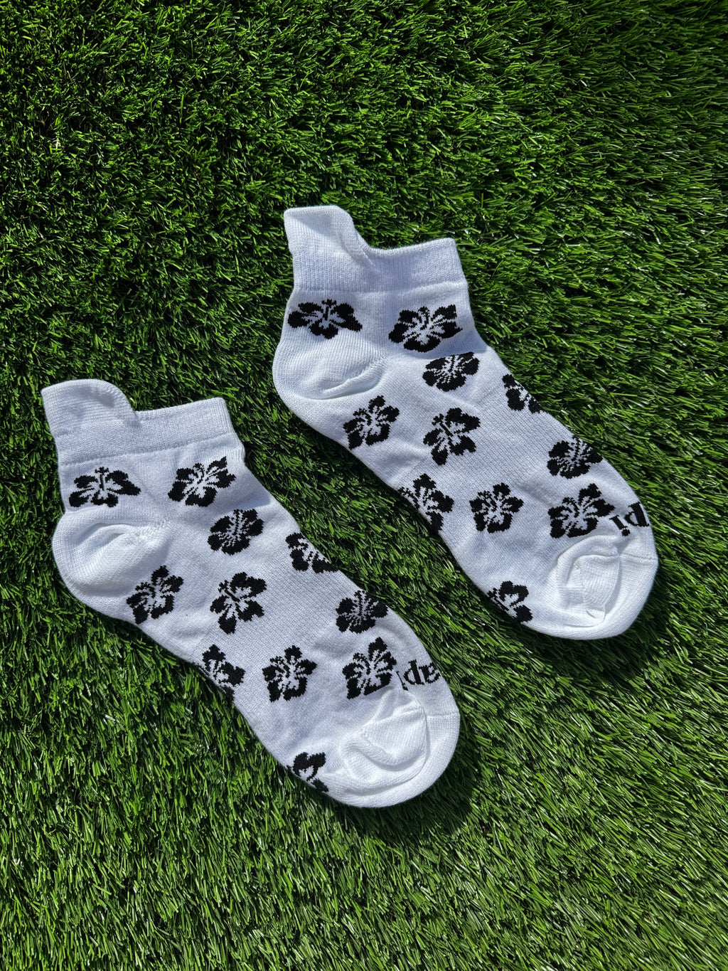 Black hibiscus ankle socks flat lay showing full hibiscus flower pattern detail