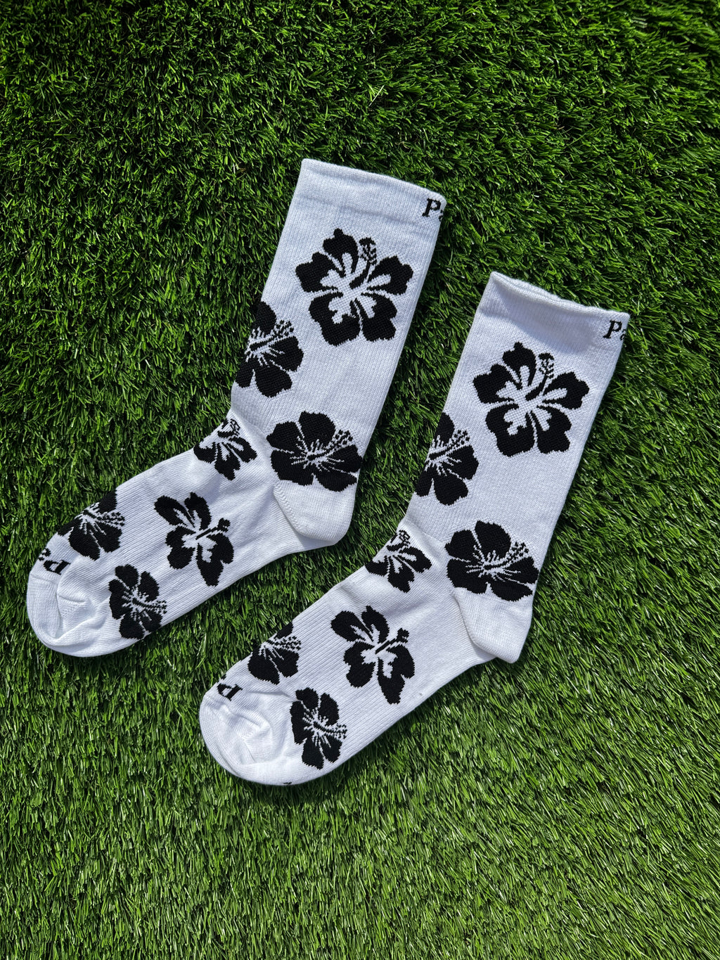 Black hibiscus crew socks side view showing tropical floral design, premium combed cotton