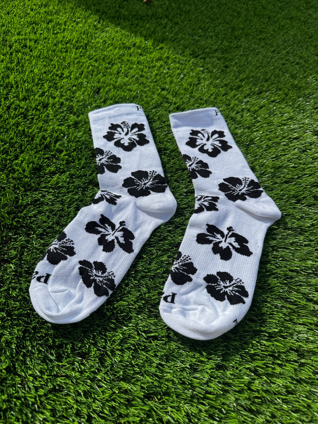 Black hibiscus crew socks flat lay showing full hibiscus flower pattern detail